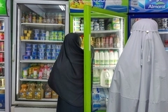 People in robes looking at a refrigerator People in robes looking at a refrigerator