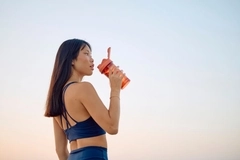 A beautiful woman drinks a supplement in the sun after exercising.