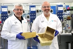 Two men wearing lab coats holding boxes.