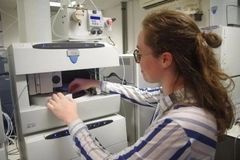 Woman uses and stands in front of tall machine