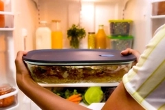 Placing lid-sealed glass container filled with food in fridge.