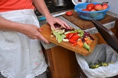female hand disposing of organic waste in a clean bin with kitchen in the background