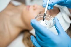 An esthetician making a face peel in a bowl.