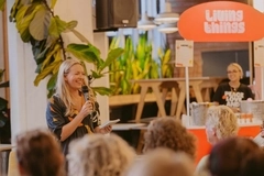A woman holing a microphone speaking to a crowd and smiling.