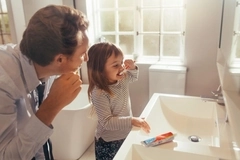 A father and daughter brushing their teeth together. A father and daughter brushing their teeth together.