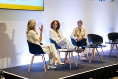 three women sitting on stage for a talk show