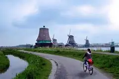 woman biking in field with dutch wind mills