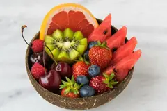 berries, cherries and orange slices in coconut shell bowl