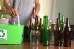 man sorting glass bottles into recycled bin