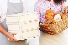 Two people holding baskets of bread and boxes of food