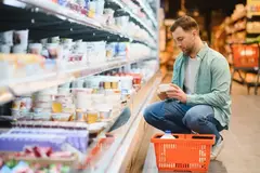 A man reads the nutritional information on a tub of yogurt in the dairy aisle.