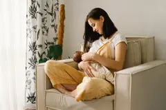 woman on chair couch breastfeeding baby