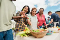 Multigenerational Multiracial people doing barbecue at home's rooftop, preparing veggies on table