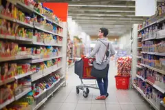 woman searching for product on supermarket shelf