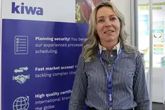 woman in a grey formal shirt standing at a trade show booth