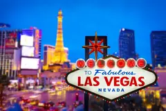 The sky line of Las Vegas at dusk with the iconic Las Vegas sign in the foreground.
