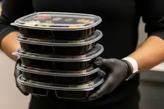 A person holding a stack of food containers
