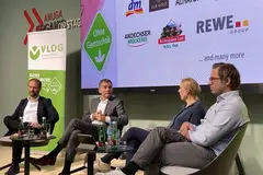 four men sitting on chairs on stage during panel discussion