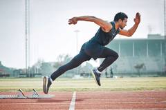 A man takes of for a sprint in an olympic style running competition.