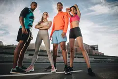 4 fitness people standing and posing together after workout