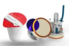 A cup with a lid next to a circular section of a machine