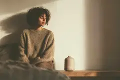 A woman sitting on the ground next to a diffuser.