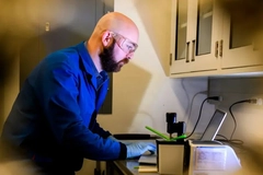 A person wearing safety glasses and gloves looking at a computer.