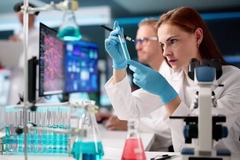 A scientist looking intensely at a test tube while in a lab.