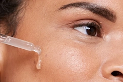 A girl putting a serum on her cheek.