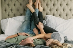 A couple in bed with their feet up on the headboard.