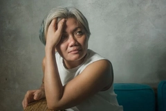 woman sitting on the couch with hand over forehead