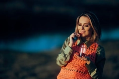 A woman prepares to eat a gummy supplement while standing in an open field. A woman prepares to eat a gummy supplement while standing in an open field.