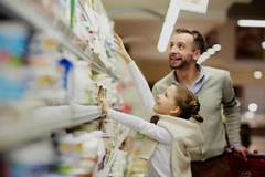 Man and girl getting products from dairy shelf.