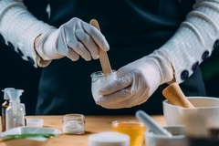Woman making organic cosmetics with gloves on. Woman making organic cosmetics with gloves on.