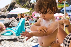 baby applying sunscreen on the beach