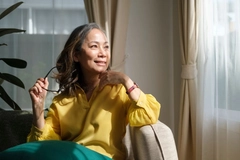 Image Middle aged woman resting on comfortable couch, looking away thinking dreaming enjoy stress free peaceful mood