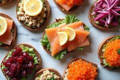 Image Various open faced sandwiches with salmon beetroot and roe eggs on dark rye bread. Served with lemon slices and lettuce on white marble table.