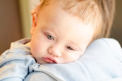 Image Sick baby boy lays head on mothers shoulder