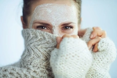 A woman with a facemask on covering half we face with her sweater.