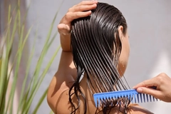 Image A woman combing her wet hair.