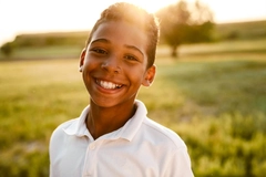 Black boy wearing white shirt smiling and looking at camera