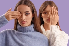Image Two women wearing makeup and each covering one of their eyes.