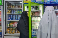 arab man and woman standing near fridge in supermarket