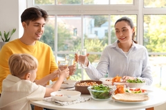 Little boy and his parents with glasses of water eating at table in kitchen
