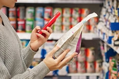 woman's hand scanning food package with smartphone inside supermarket