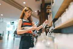 A woman shopping and holding two products.