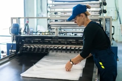 Image A person in a blue hat working on a sheet of plastic