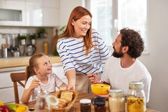 mother, father, daughter eating breakfast on table with cereal