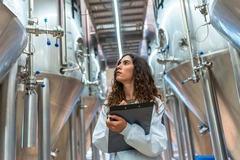 female scientist with fermentation tanks young female scientist in factory with fermentation tanks