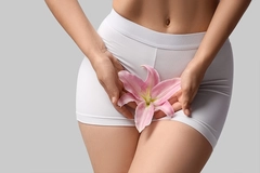 young woman in panties holding flower over her pelvis